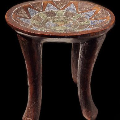 Wooden stool with intricate decorative top.