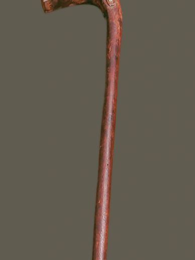 Old wooden walking cane with a curved handle.