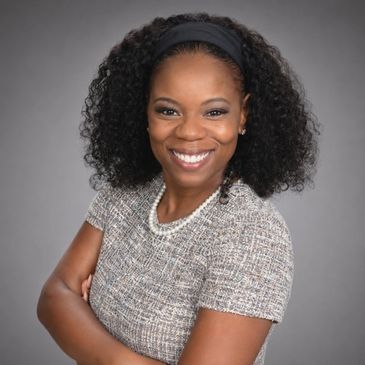 Confident woman with curly hair smiling in professional attire.