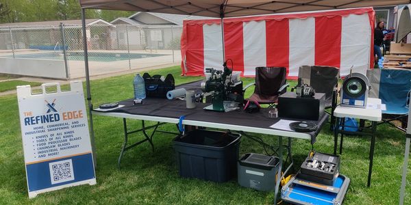 Outdoor sharpening service booth with tools and equipment under a canopy. knife's edge