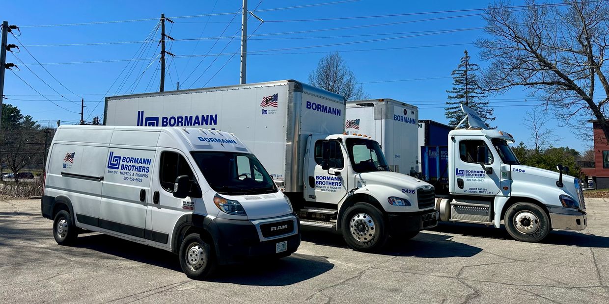 Three Bormann Brothers moving trucks parked outside on a sunny day.