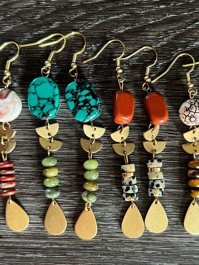 Handmade colorful beaded earrings with gold accents on a wooden surface.