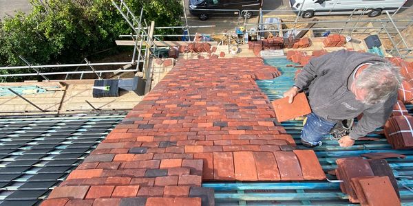 Worker placing roof tiles