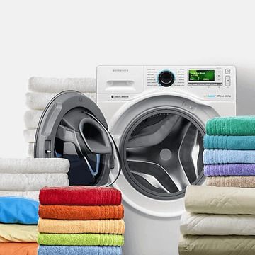 Front-load washing machine with colorful folded towels stacked nearby.
