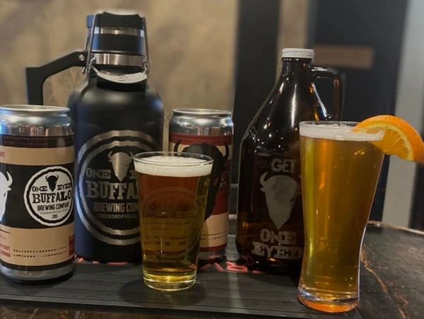 Craft beers and growlers from One Eyed Buffalo Brewing Company on a wooden table.