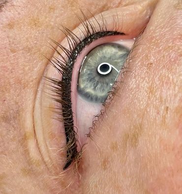 Close-up of a blue-gray eye with eyeliner and long eyelashes.