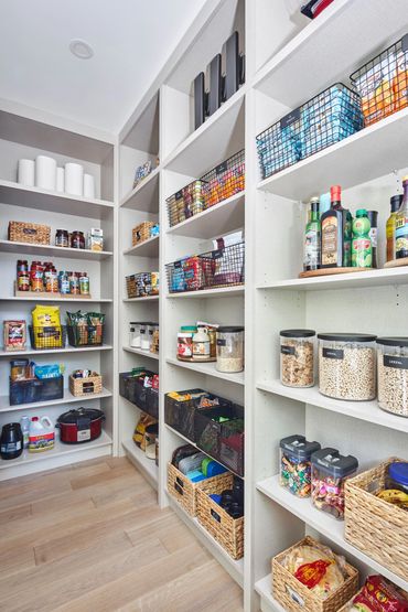 Well-organized pantry with labeled baskets and containers for food storage.