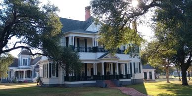 A very large Colonial style home, white with tall columns on the front porch.