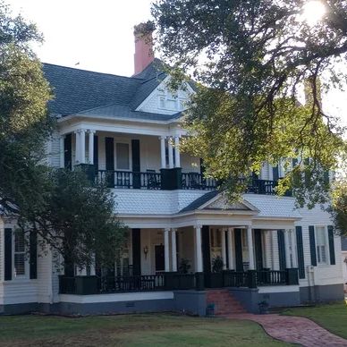 Large white two-story house with a porch.