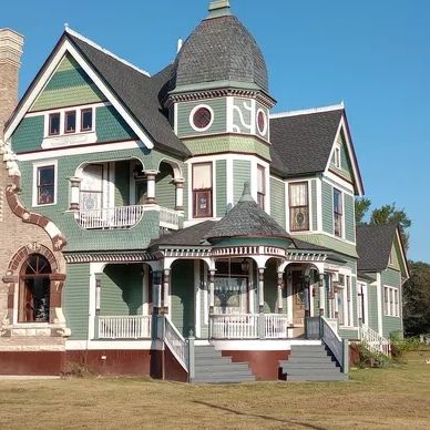A large 3 story Victorian home with ornate trim and a large curved chimney.
