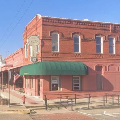 Old brick building with green awning on a sunny day.