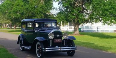 A 1930s sedan driving down a Calvert street in contemporary times.