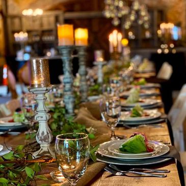 Elegant dining table set with candles and fresh salad plates for a formal event.