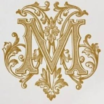 Ornate golden letter M with floral and scrollwork design.