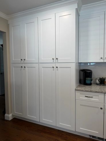 Tall white kitchen cabinets with silver knobs.