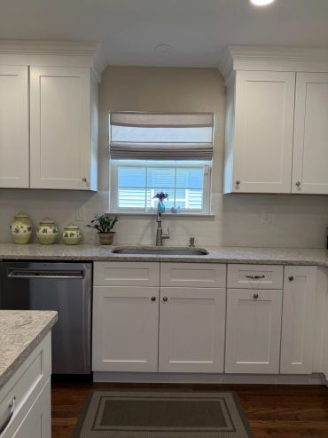 Modern kitchen with white cabinets and marble countertop.