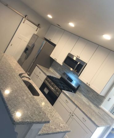 Modern kitchen with white cabinets and granite countertops.