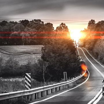Sunset over a winding road through the forest.