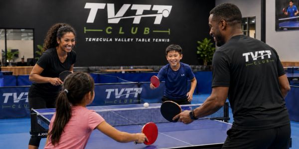 A family enjoys a lively table tennis game at TVTT Club.