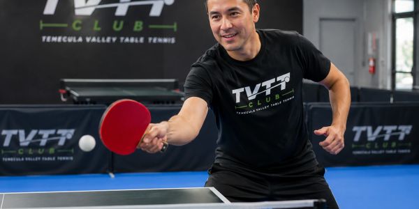 Man playing table tennis at TVTT Club with focused expression.