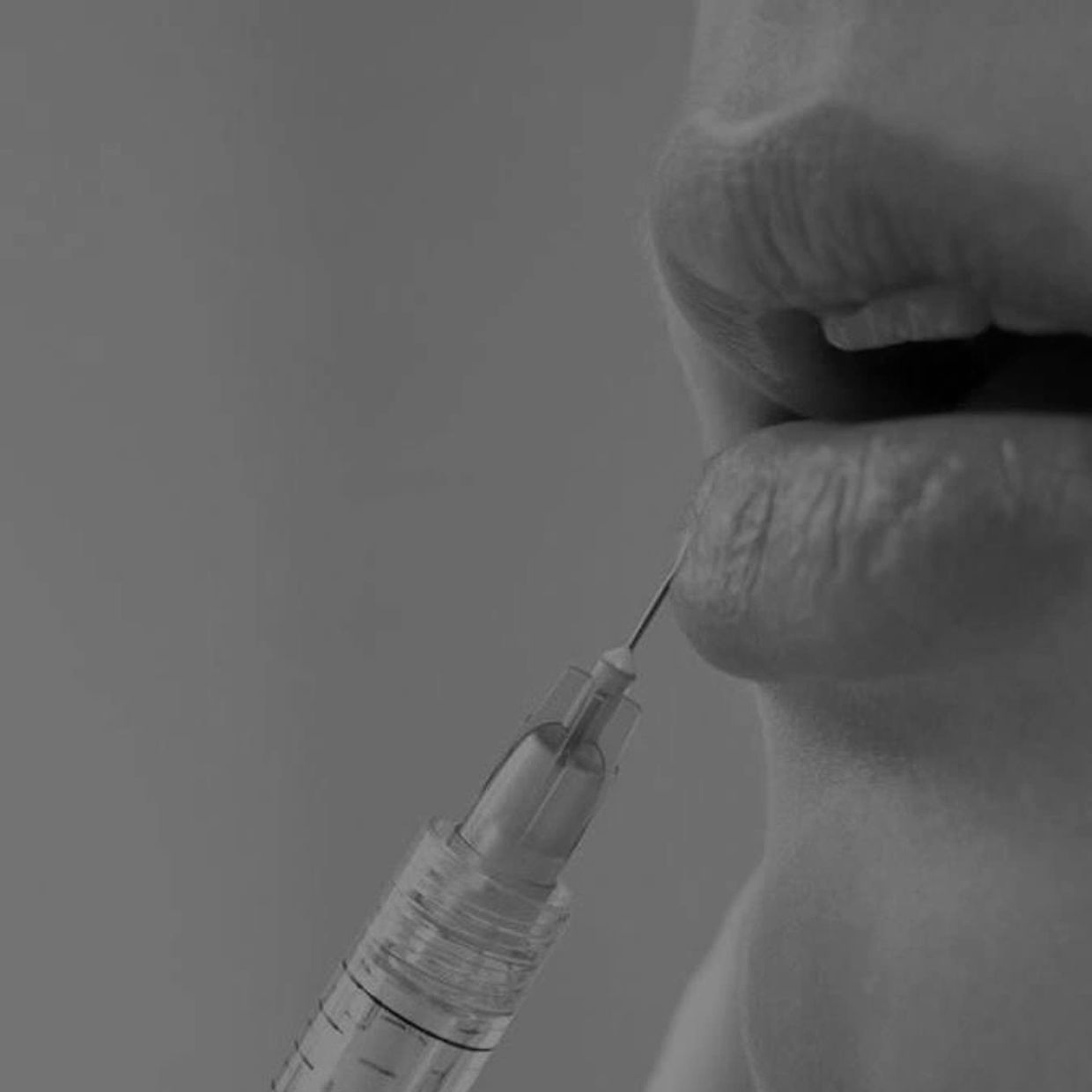 Close-up of lips with a syringe needle near them.
