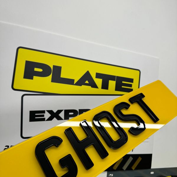 Glossy yellow license plate with black letters reading 'GHOST'.