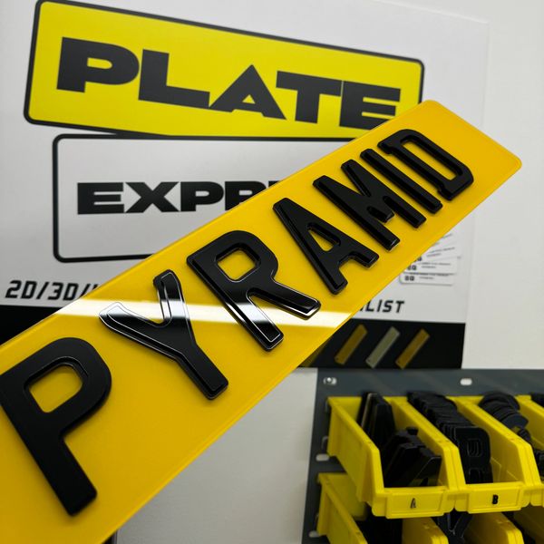 Custom yellow license plate with raised black letters spelling PYRAMID.