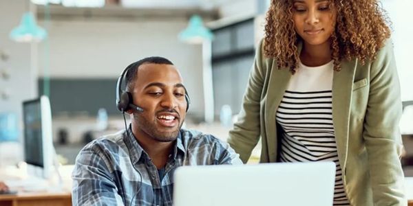 Two colleagues collaborate at a laptop in a modern office setting.
