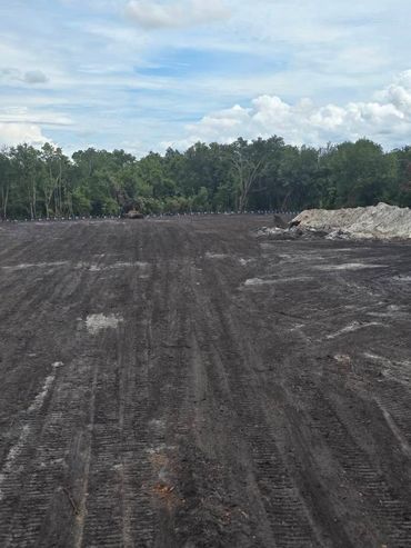 A large cleared dirt area with tire tracks and trees in the background.