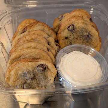 Chocolate chip cookies with frosting in a plastic container.