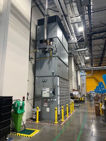 Large industrial HVAC unit inside a warehouse with safety barriers.