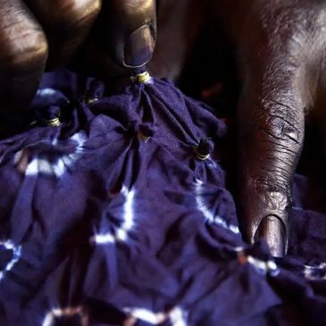 Close-up of hands working on indigo fabric with knots.