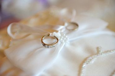 Close up shot of wedding rings on satin pillow.