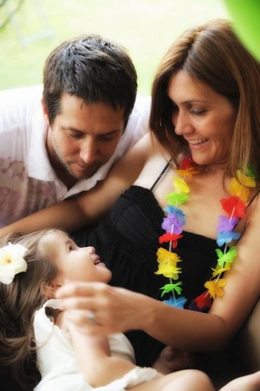 Intimate portrait of parents looking lovingly at young daughter.