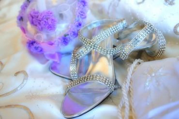 Close up of blinged out wedding high heeled shoes on satin pillows.