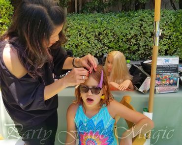Cassie applying hair tinsels to a guest during a glitzy Los Angeles event.