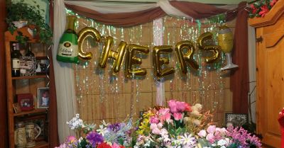 Cheers balloon garland hanging in front of a tinsel backdrop