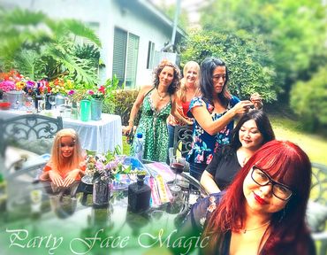 Cassie applying hair tinsels to Stephanie while other guests are enjoying the garden birthday event.