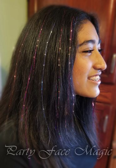 Blue and pink hair tinsels applied to brunette hair.