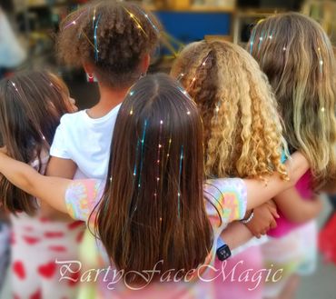 Birthday girl and friends in a big group hug, showing off their new hair tinsels.