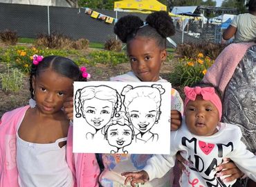 Two African American little girls and their baby sister holding up their caricature drawing.
