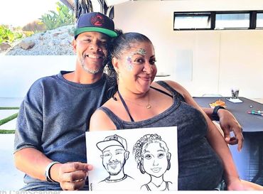 An African American couple smiling and posing together with their caricature drawing.