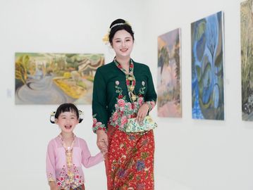 Two women smiling together surrounded by white orchids.