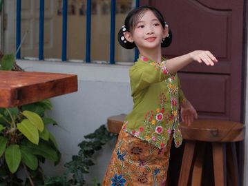 Young girl in traditional attire performing a dance gesture.