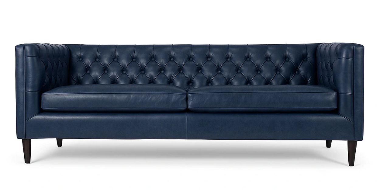 Elegant navy blue tufted leather sofa with wooden legs.