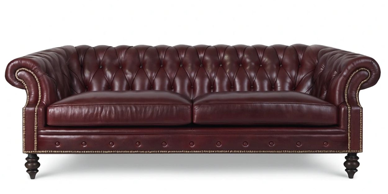 A classic dark brown leather Chesterfield sofa with tufted back and rolled arms.