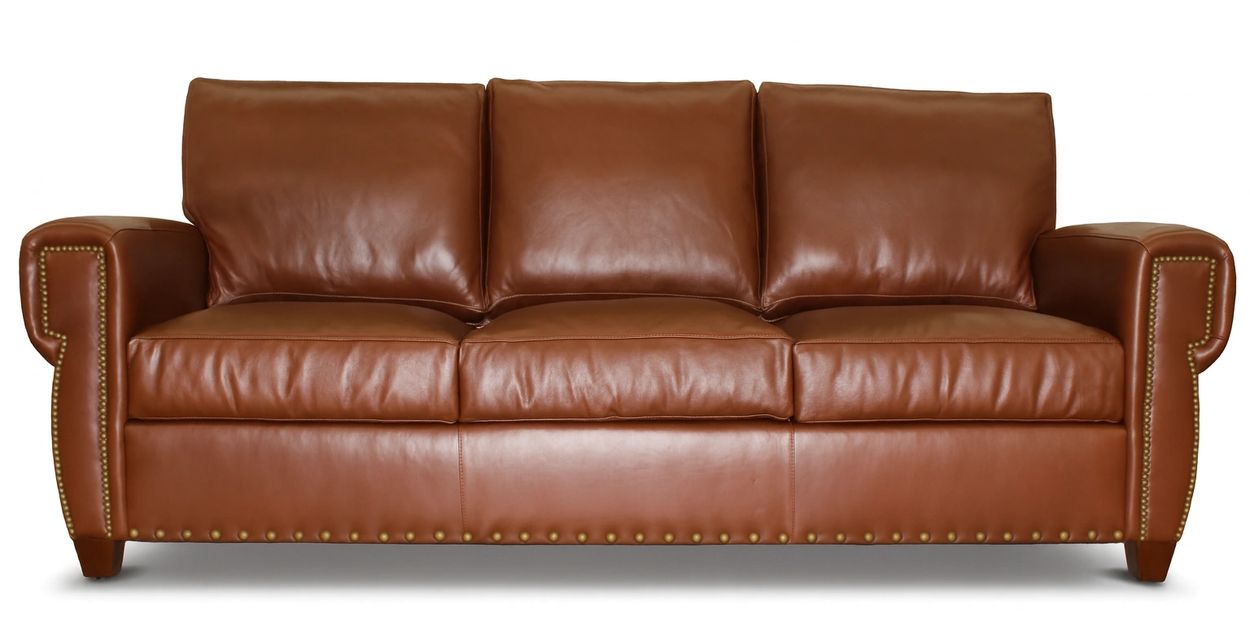 Brown leather sofa with nailhead trim and three cushions.