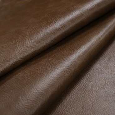 Close-up of brown leather fabric with texture and folds.