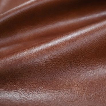 Close-up of smooth brown leather texture with natural creases and shine.