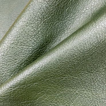 Close-up of shiny olive green leather texture with natural grain.